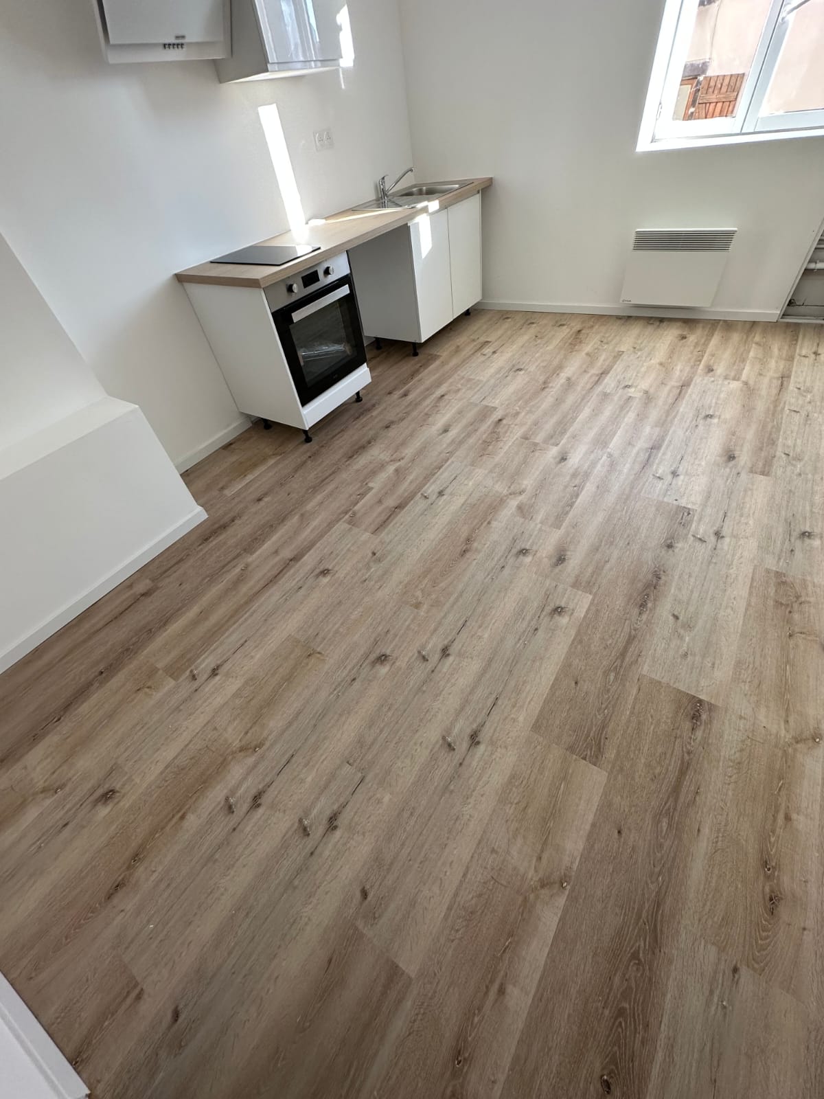 Salle de cuisine avec sol en PVC imitation bois clair, finition mat, après travaux.