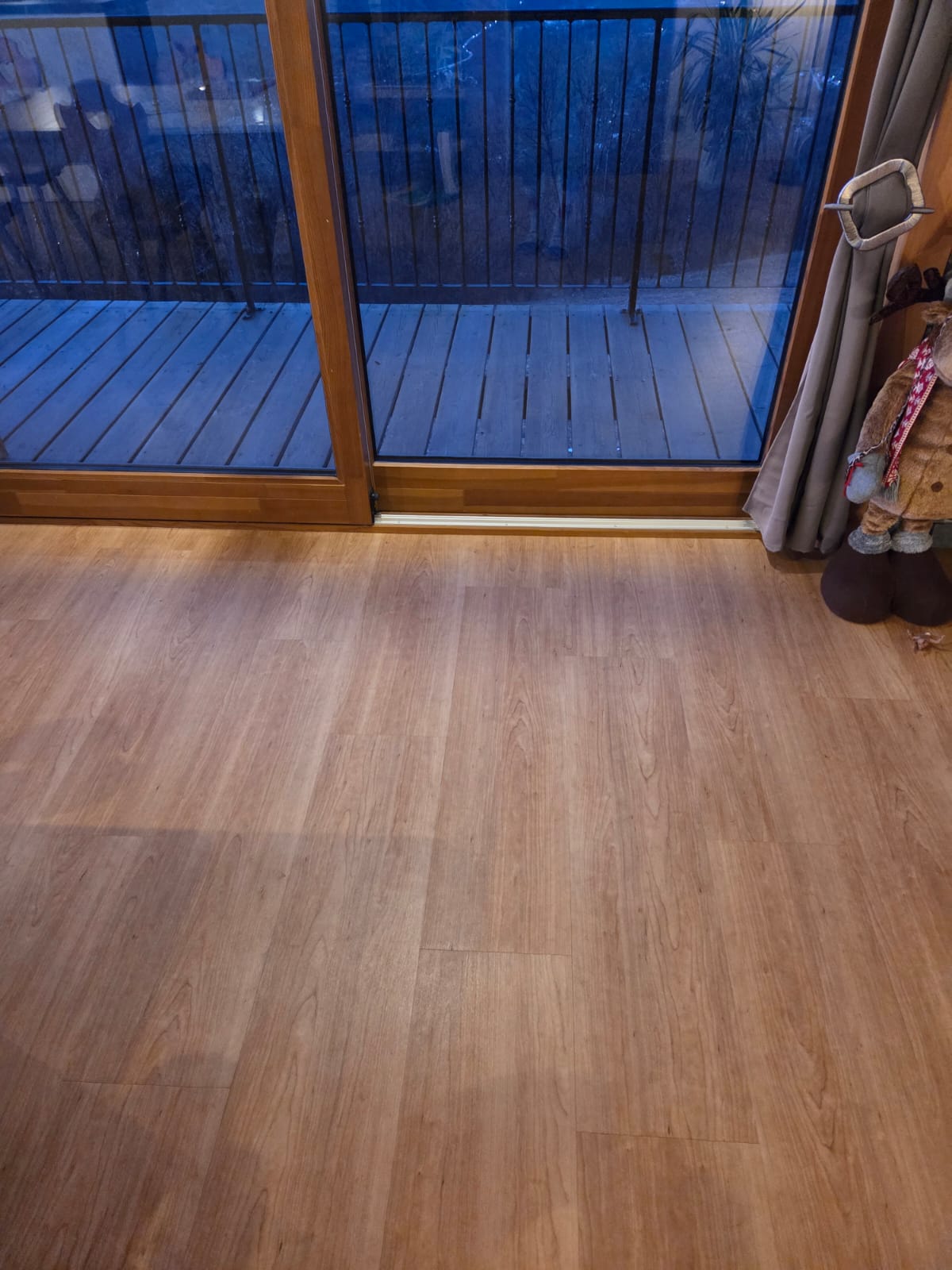 Salle de séjour avec sol en PVC imitation bois clair et vue sur balcon en bois